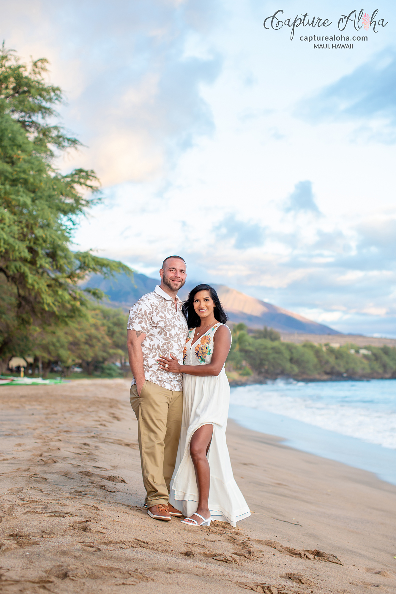 A couple on the beach in Maui with West Maui mountains behind them