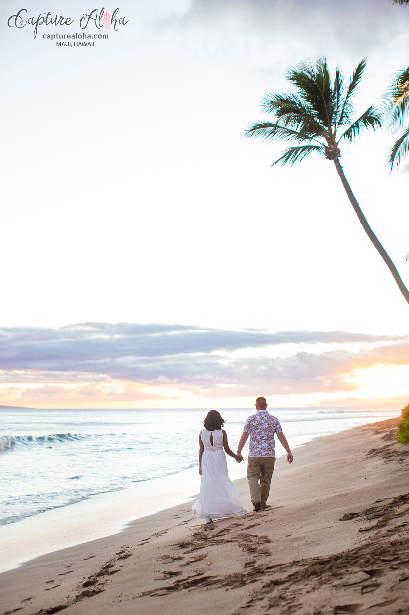 Husband and wife holding hands walking down a Maui Beach at Sunset 