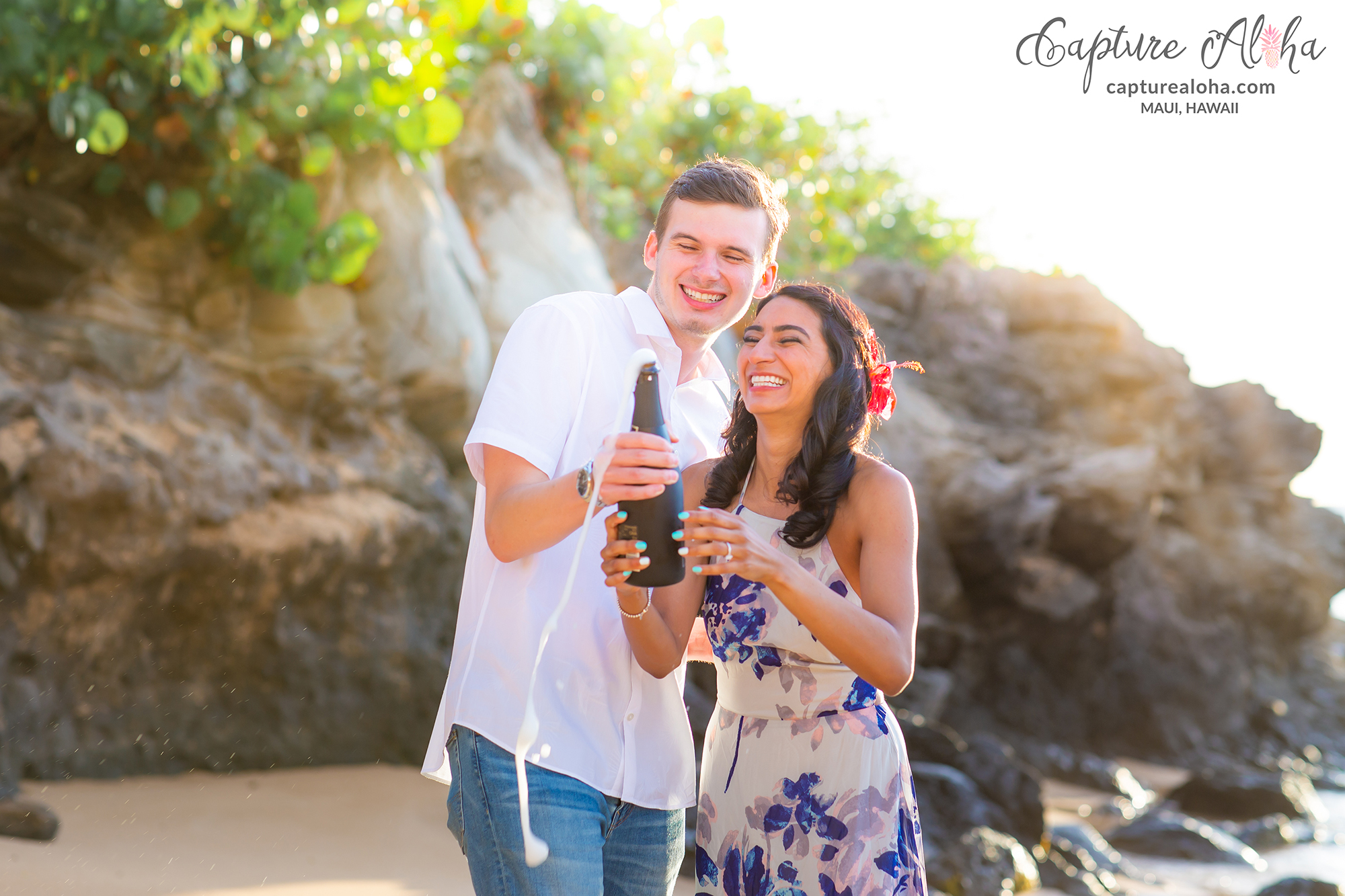 Maui couples portraits at Kapalua with couple celebrating engagement with champagne on the beach