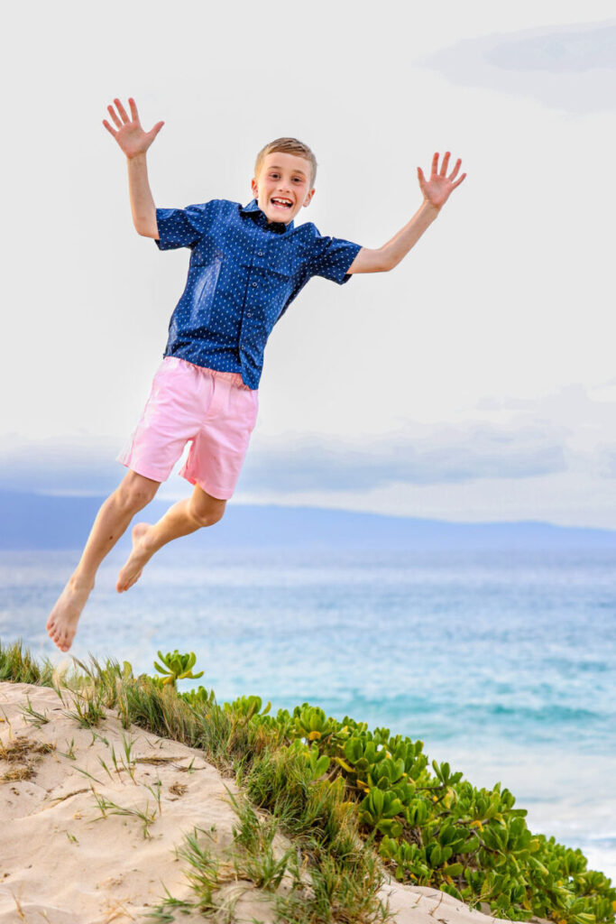 boy jumping in the air on the beach on Maui