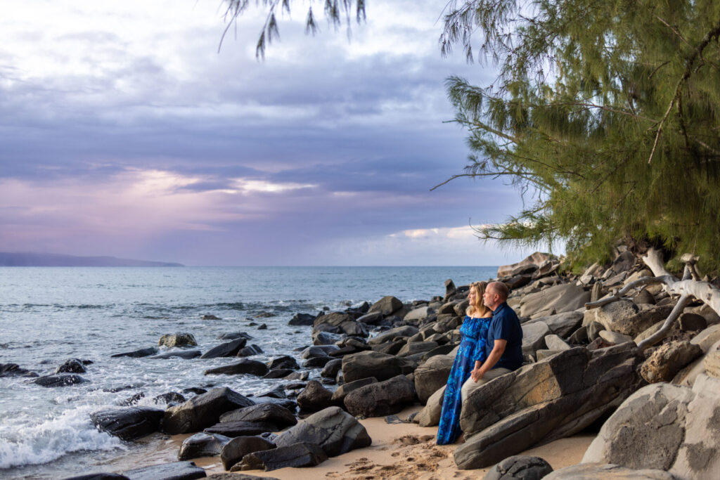 Portrait of a couple at DT Fleming Beach framed by sunset colors and ocean waves