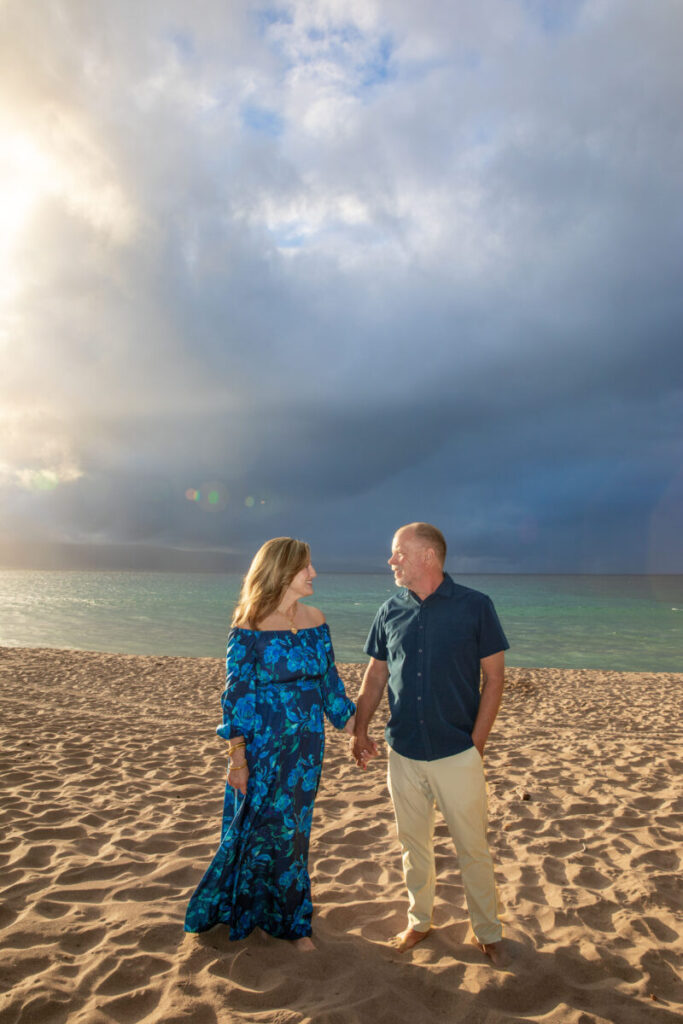 Portrait of a couple at DT Fleming Beach framed by sunset colors and ocean waves