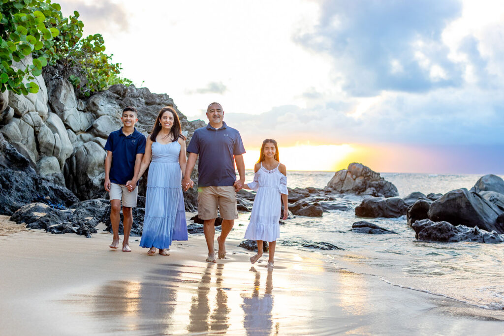 Family walking along Kapalua Bay shoreline during golden hour in Maui