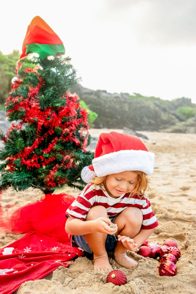  child playing on the shoreline, creating timeless holiday cards in Maui
