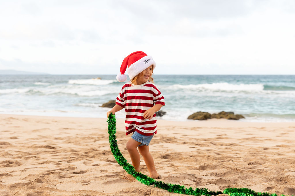  child playing on the shoreline, creating timeless holiday cards in Maui