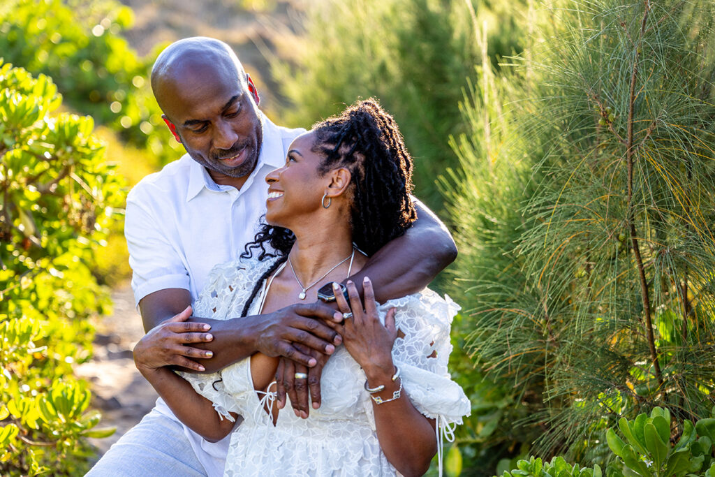 Couple looking into each other’s eyes while holding hands during a Maui couple photo session in lush greenery