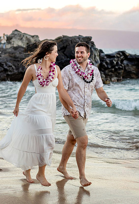 Playful Maui couple photo session with a couple walking hand in hand by the ocean shoreline.