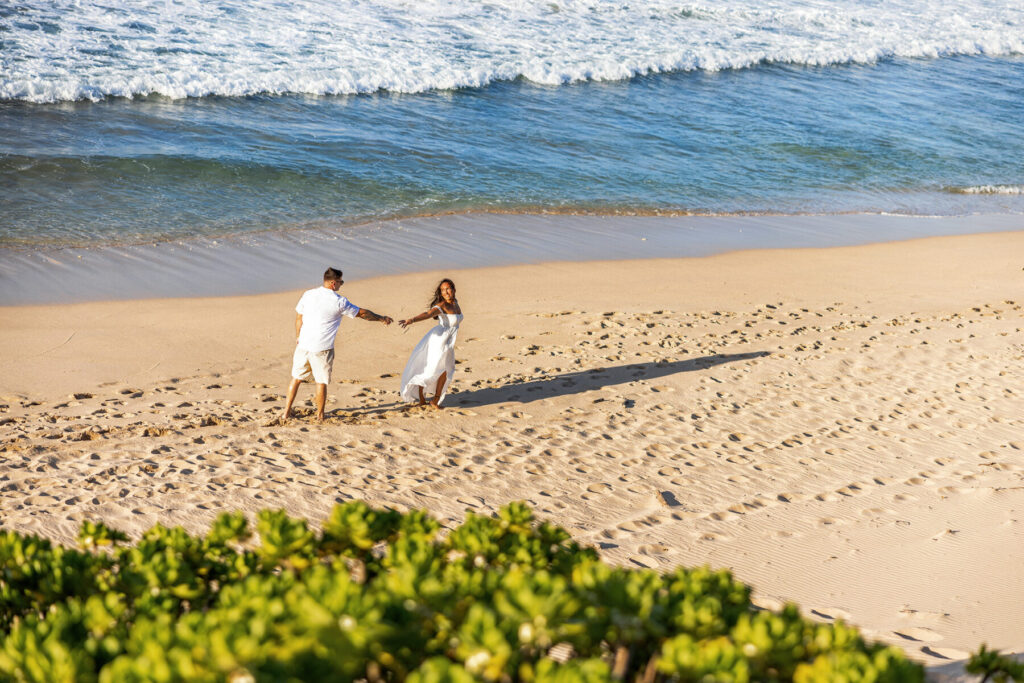 Maui couples session at Ironwood Beach – engaged pair walk barefoot by lava rocks and soft surf at sunset, candid romance in West Maui.