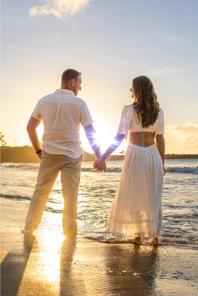 Romantic Maui couple photo session on the beach at sunset with warm golden light reflecting on the ocean waves.
