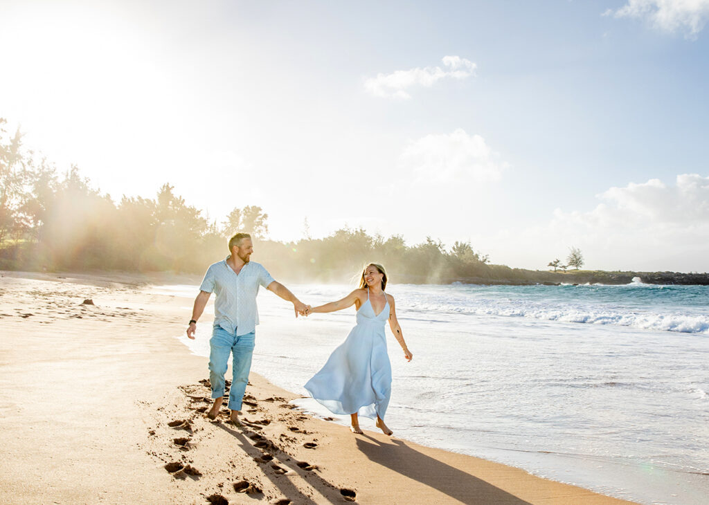 Couple holding hands during a Maui couple photo session at DT Fleming Beach as the sun sets behind them.