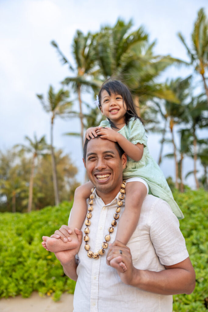 Father carrying daughter on shoulders and laughing together during Maui family photography at DT Fleming Beach.
