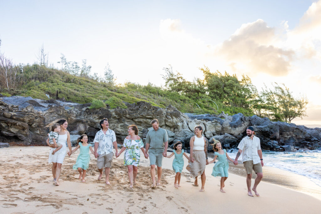 Family walking hand in hand by the rocks at DT Fleming Beach during golden hour, a natural scene at one of the Top Maui Photoshoot Locations on the West Side.