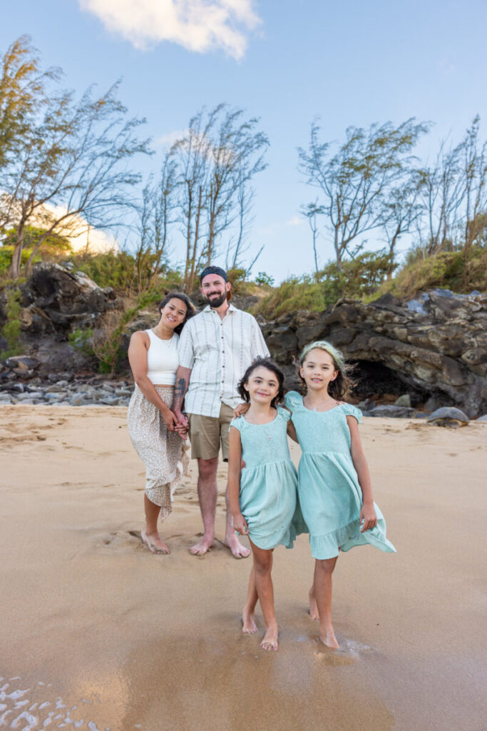Family standing on the sand as two young girls walk toward the camera at DT Fleming Beach, capturing candid moments at one of the Top Maui Photoshoot Locations.