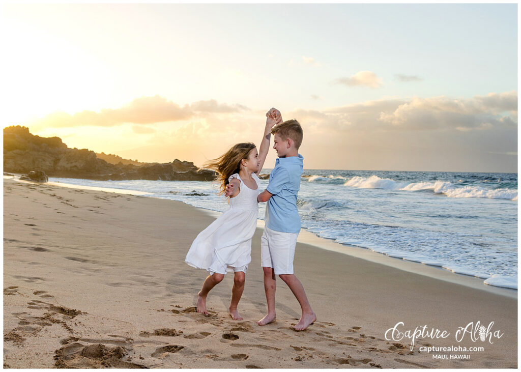 Maui Kids Photography session of two siblings dancing together at Ironwoods beach at sunset, highlighting movement, connection, and playful family fun.