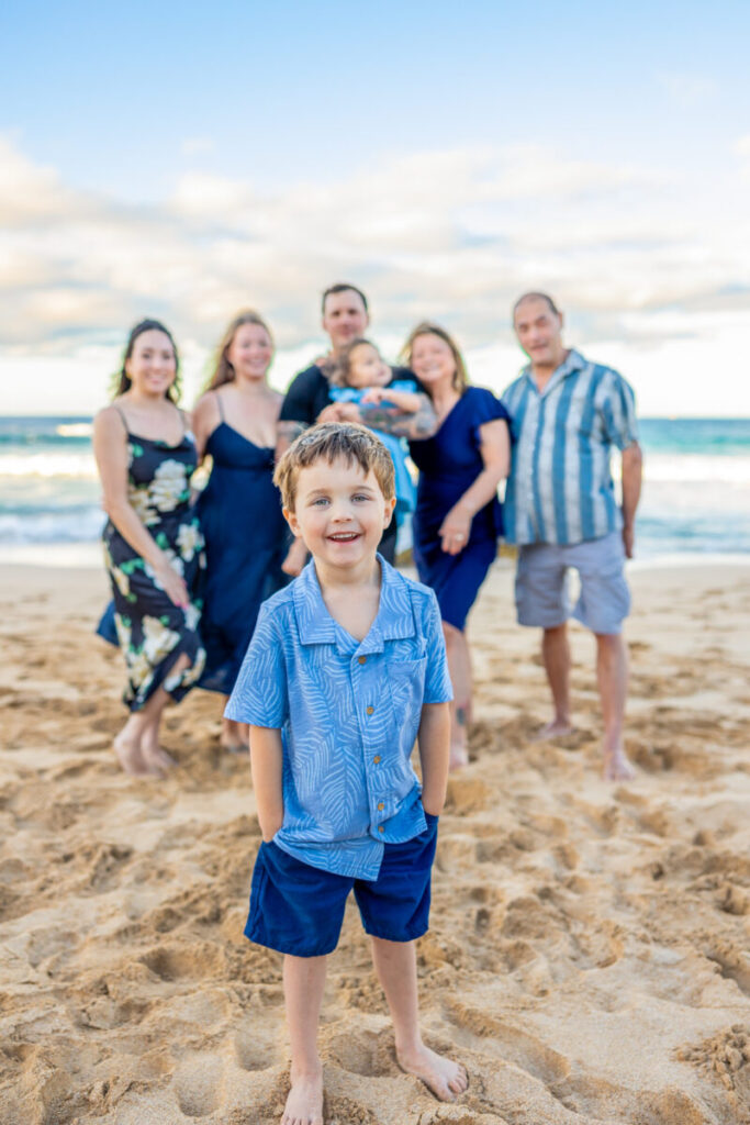 Maui Kids Photography portrait of a young boy smiling confidently in front of his family during a Maui beach photoshoot with playful, relaxed energy.
