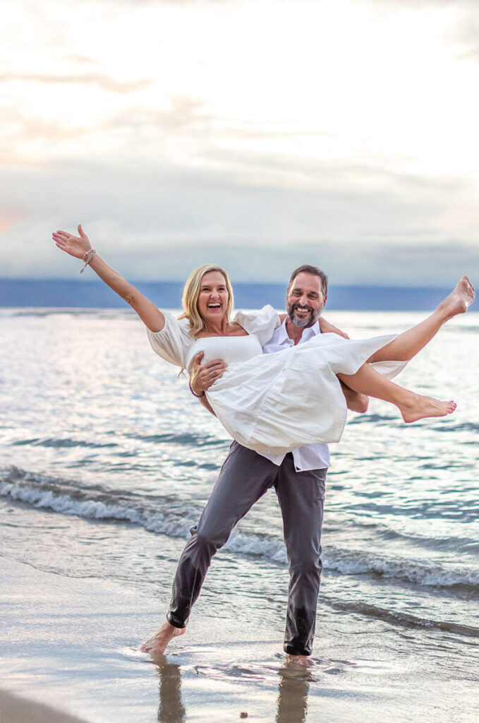 Maui couples session at sunset with a joyful couple in the surf, lifted and laughing.