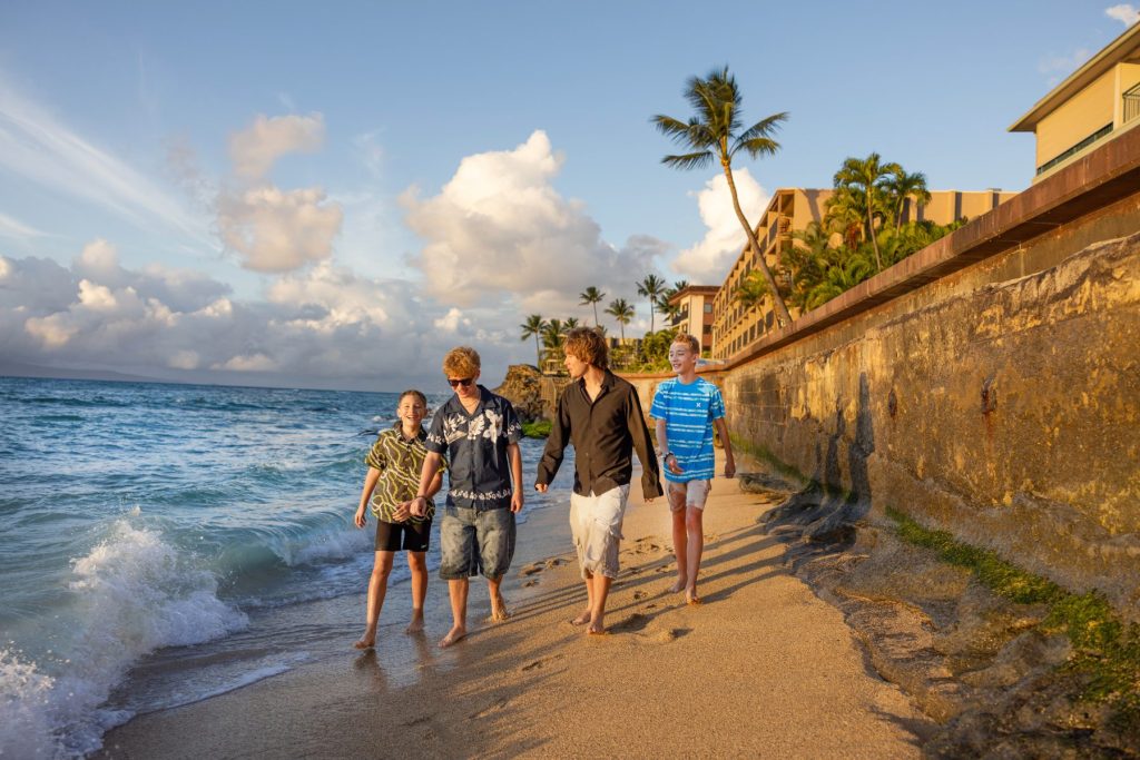 Maui family photoshoot at Honokōwai Beach with children walking barefoot along the shoreline at sunset.