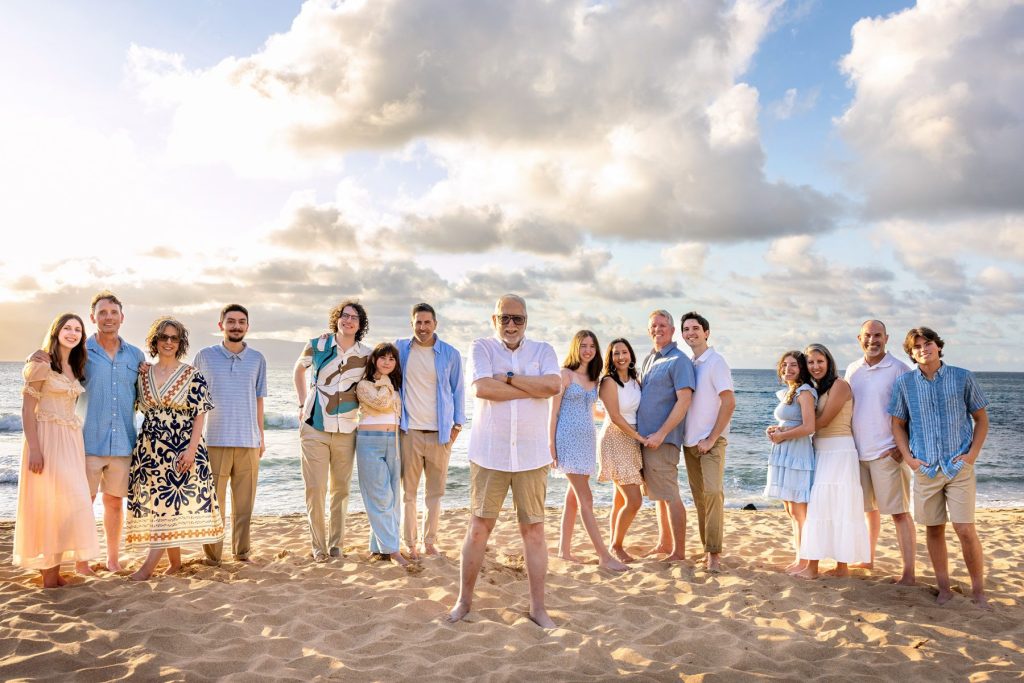 Maui family photoshoot with a large extended family standing together on the beach during golden hour.