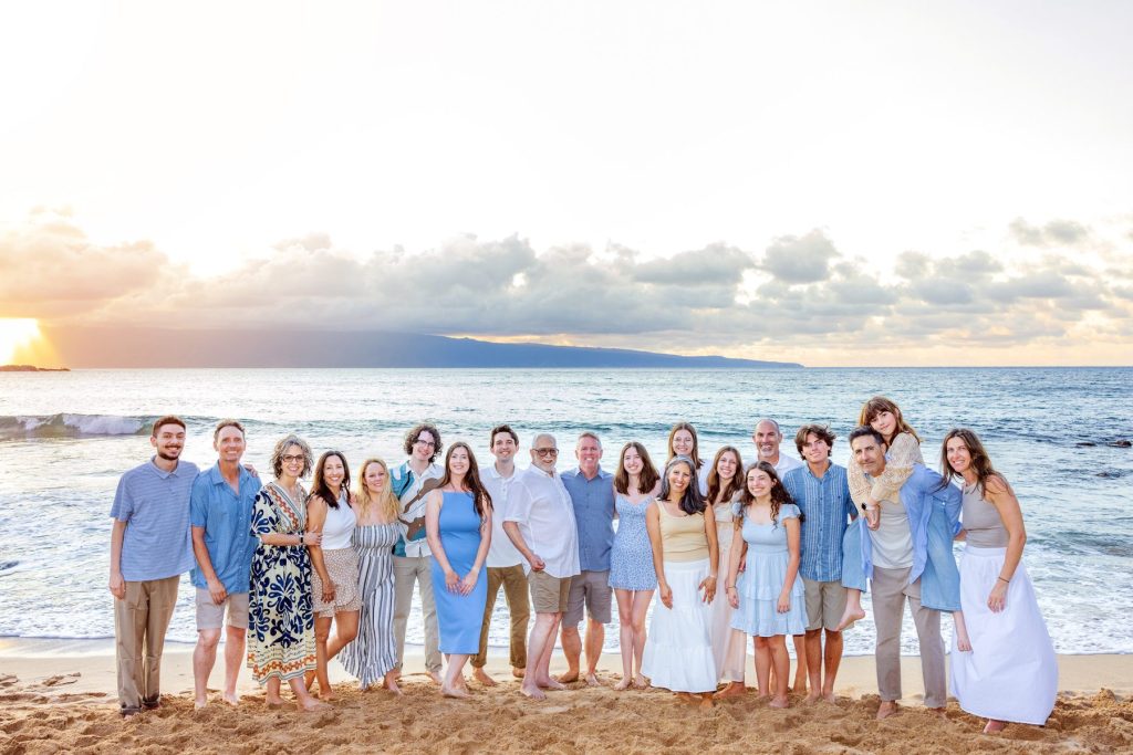 Maui family photoshoot with a large extended family standing together on the beach during golden hour.