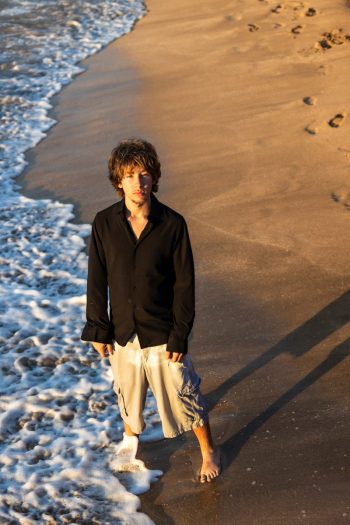 boy standing alone on the beach at sunset in Maui