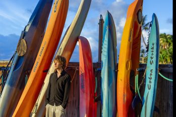 Senior posing by colorful surfboards on the beach in Maui.
