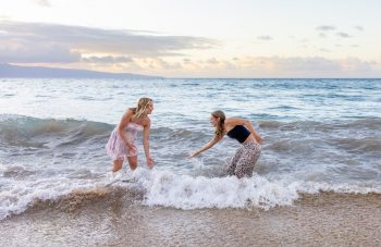 Friends splashing in ocean waves during a Maui beach photoshoot.