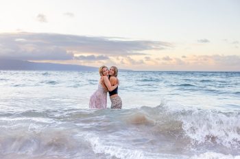 Friends embracing in the ocean at sunset in Maui.
