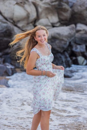 Senior girl smiling near lava rocks during a Maui beach session.