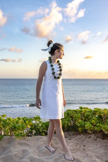 Teen girl standing by the ocean at sunset in Maui