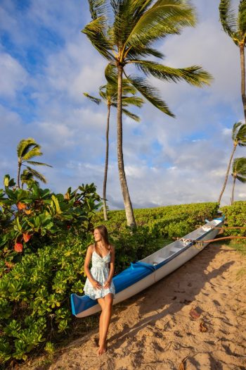Senior posing next to palm trees swaying over the beach during a Maui senior portraits photoshoot