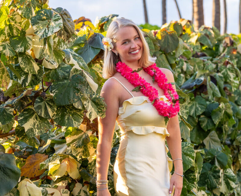 Maui senior posing with Pink lei and sun flare at Kapalua Beach
