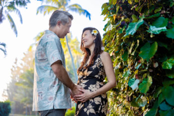 Expecting couple cradle baby bump under lush vines, maternity session, Maui.