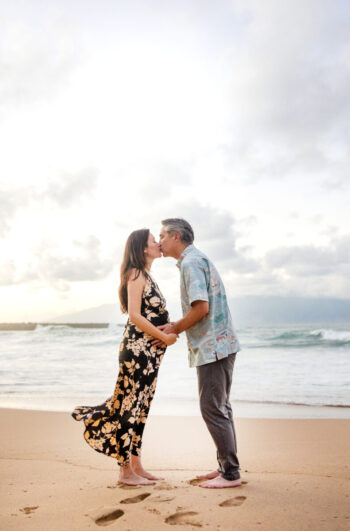 Engagement photoshoot Maui – couple kissing under streaks of golden sky.