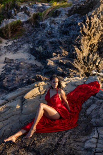 Flying dress photoshoot Maui – woman sitting on the rocks