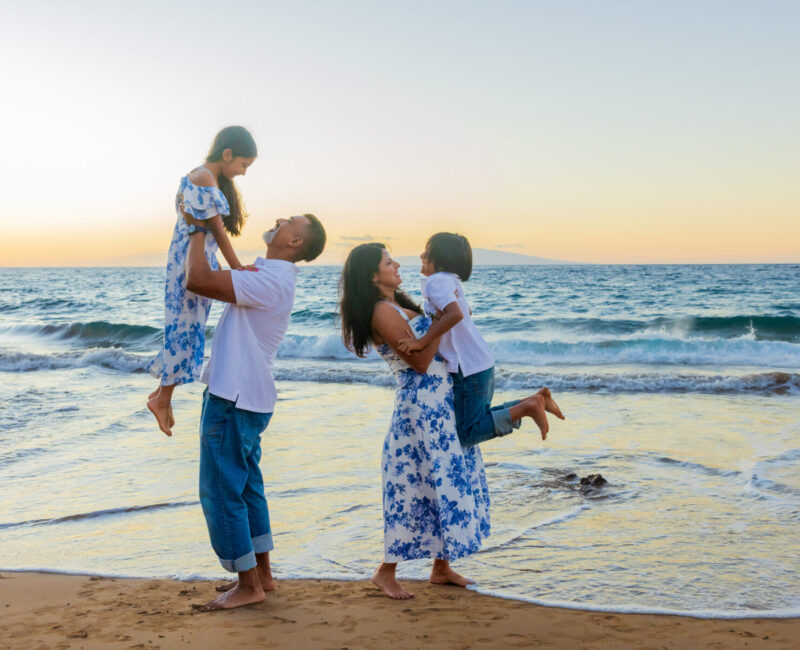 Maui beach family portraits – family of four laughing as waves roll in at Maluaka Beach