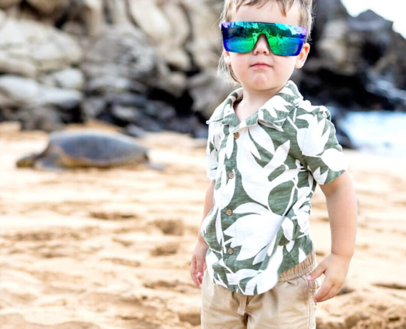 Maui child portrait – boy in sunglasses and aloha shirt on sandy beach.
