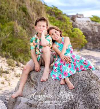 Siblings in floral design – Maui beach portrait by greenery and coastal lava rocks.