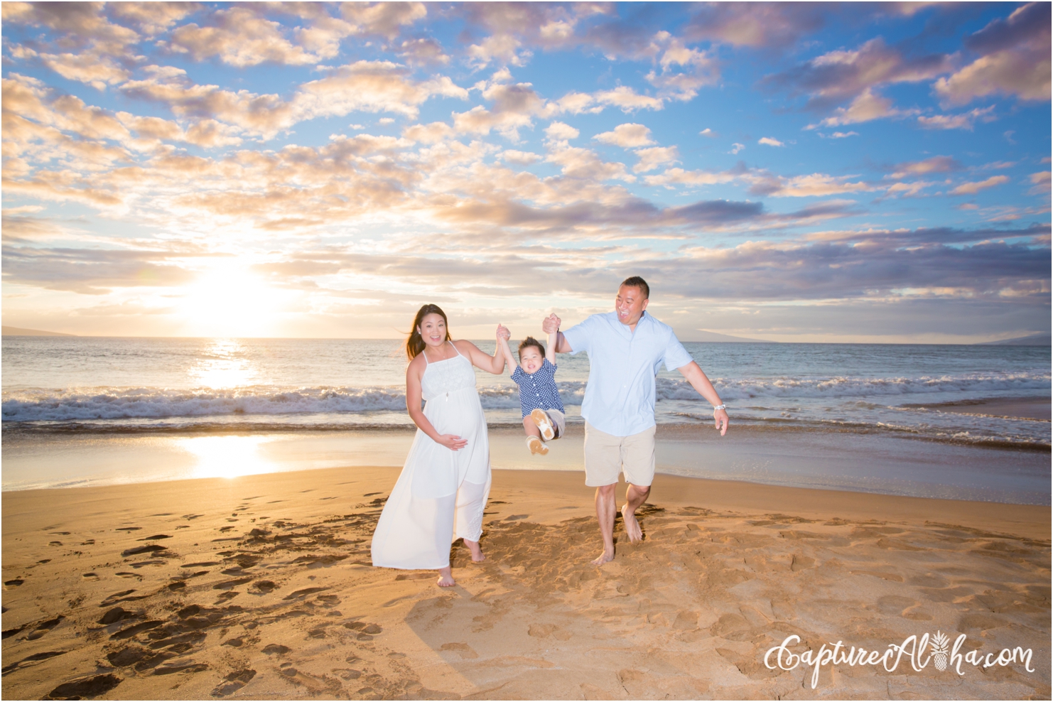 parents swinging toddler on the beach during Maui maternity photography session