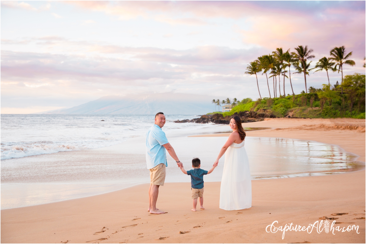 mom, dad, and toddler walking on a Maui beach at sunset