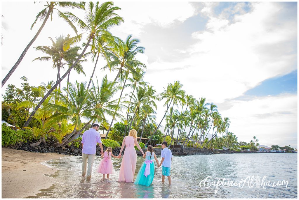 Family photography on Baby Beach in Lahaina, Maui in the morning with whole family holding hands and walking away