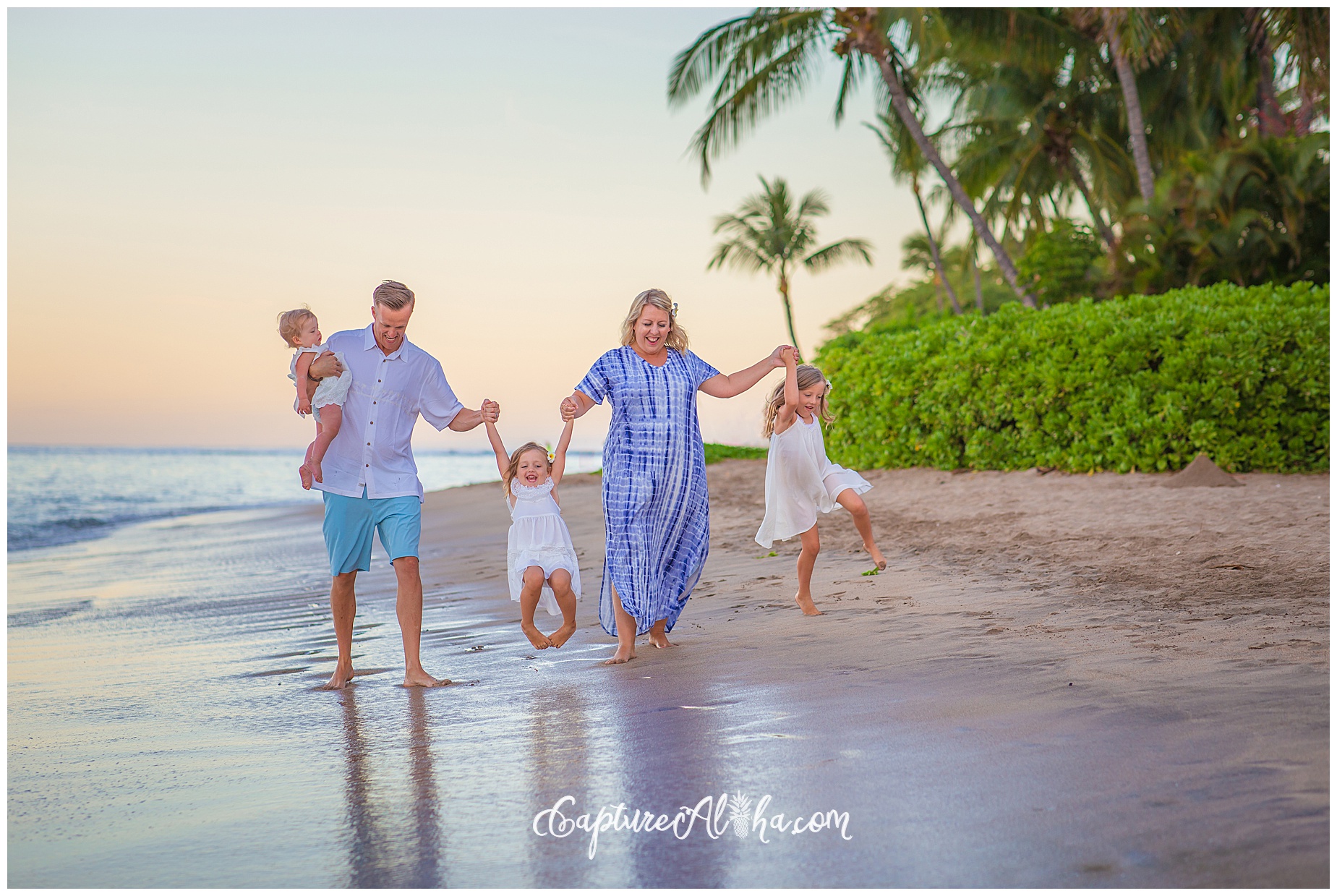 A beautiful family of 5 walking and playing on Baby Beach in Lahaina Hawaii