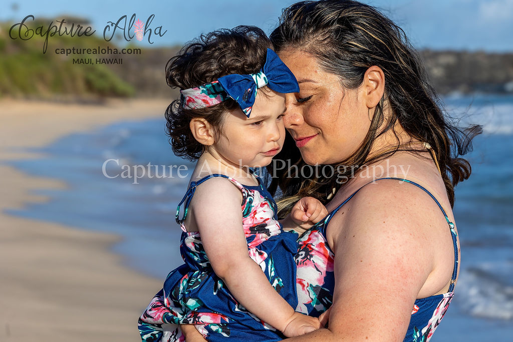 A mother holds her baby daughter on the beach on Maui.