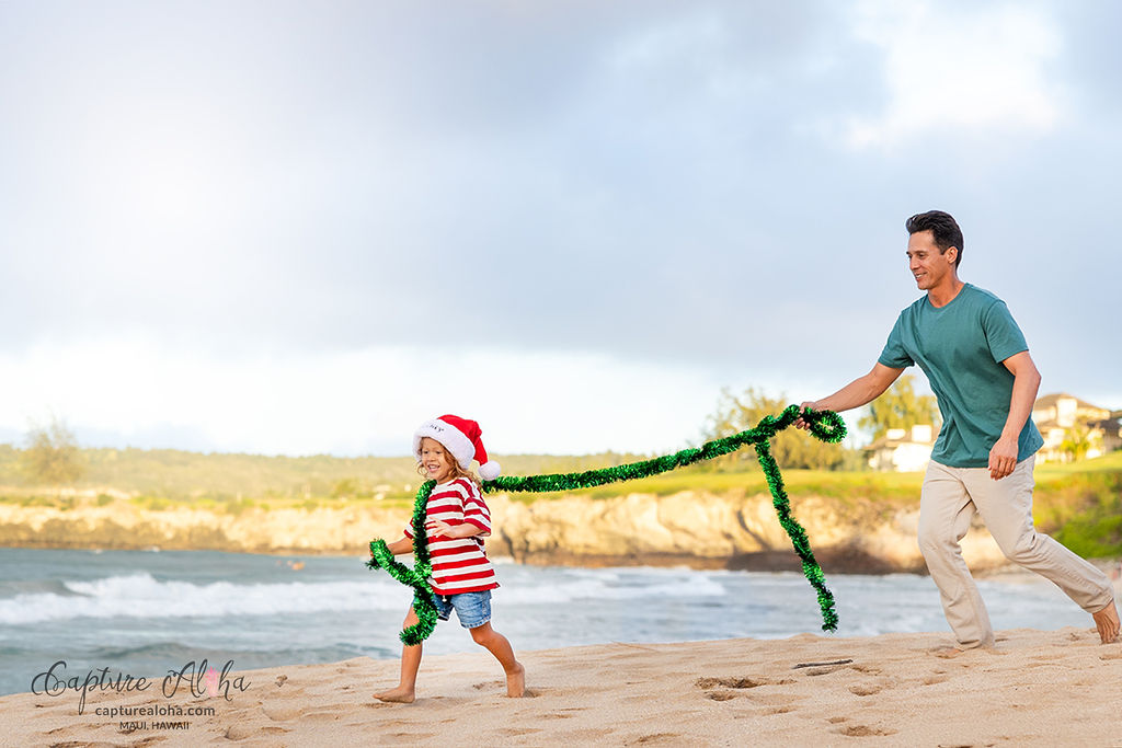 Father and Daughter playing on the beach on Maui with Christmas garland.