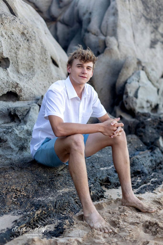 Senior portrait of a student in a scenic outdoor setting, standing confidently against a backdrop of nature. The student is dressed in a stylish outfit, with a relaxed yet confident pose. Soft, natural light highlights their features, while the surrounding landscape—whether it’s a beach, lush greenery, or distant mountains—adds depth and beauty to the image. The warm tones of the scene evoke a sense of calm and serenity, capturing the spirit of this special moment in time