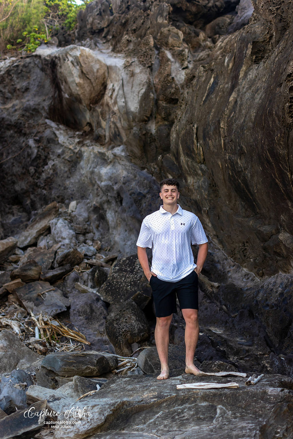 Senior portrait of a student in a scenic outdoor setting, standing confidently against a backdrop of nature. The student is dressed in a stylish outfit, with a relaxed yet confident pose. Soft, natural light highlights their features, while the surrounding landscape—whether it’s a beach, lush greenery, or distant mountains—adds depth and beauty to the image. The warm tones of the scene evoke a sense of calm and serenity, capturing the spirit of this special moment in time