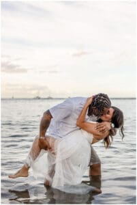 A loving couple embraces on a Maui beach during a romantic sunset photoshoot, with golden sand, gentle waves, and a breathtaking sky creating a dreamy atmosphere.