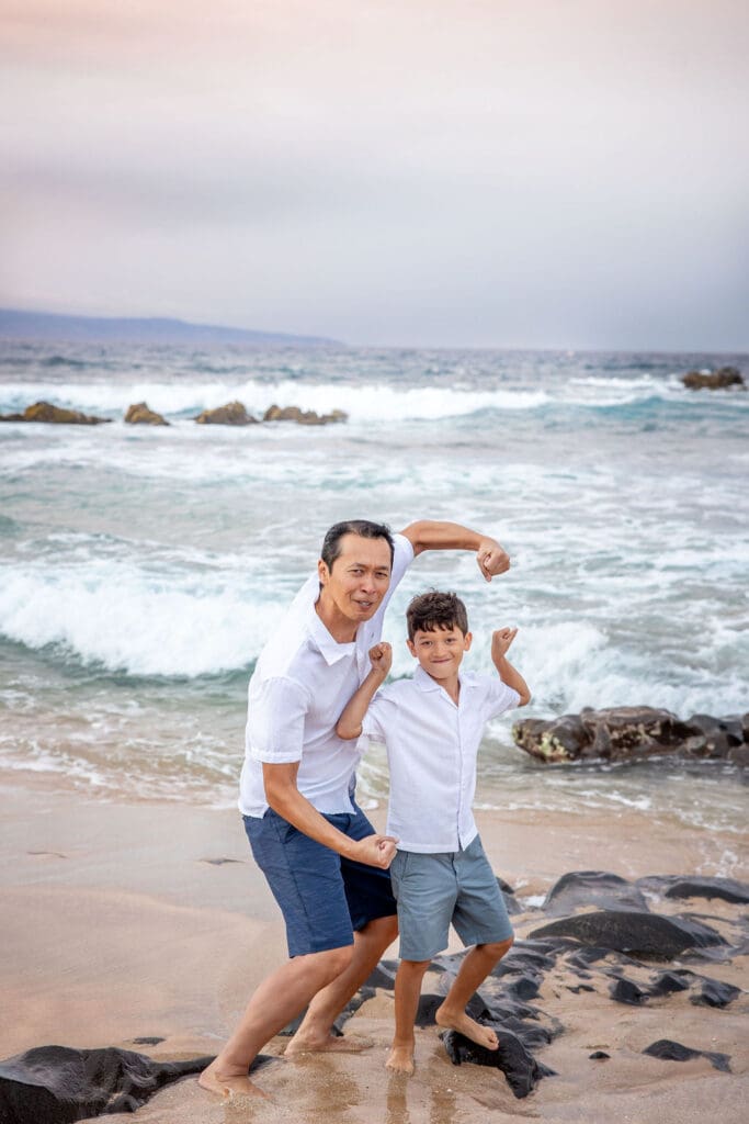  father sharing a loving moment with his son as waves gently roll in behind them.