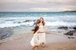 mother and daughter dancing on Maui beach at sunset